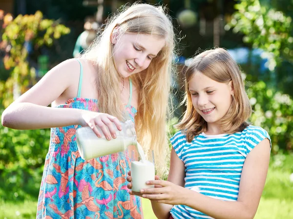 Deux filles verse du lait dans une prairie ensoleillée — Photo