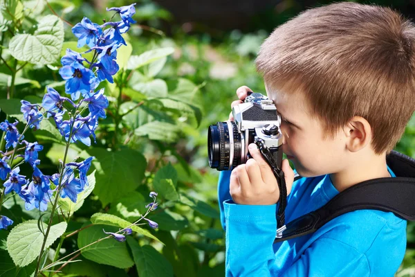 Menino com câmera retro atirando flores — Fotografia de Stock