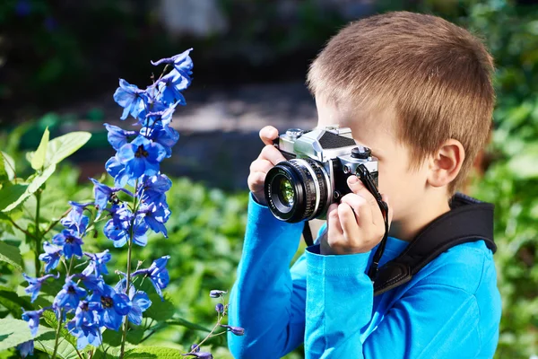 Petit garçon avec caméra rétro tirant des fleurs — Photo