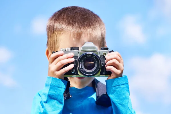 Malý chlapec s retro Slr fotoaparát na modré obloze — Stock fotografie