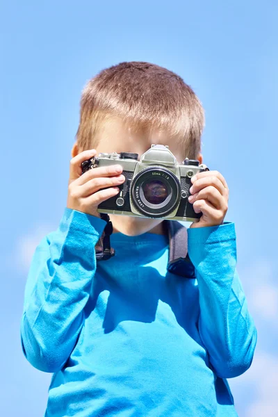Liten pojke med retro Slr kamera på blå himmel — Stockfoto