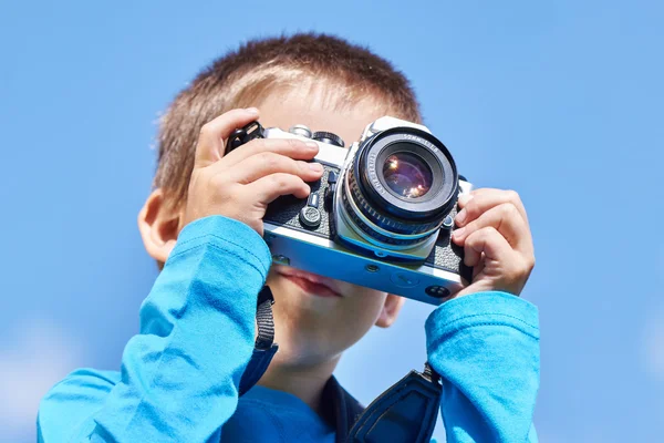 Kleiner Junge mit Retro-Slr-Kamera am blauen Himmel — Stockfoto