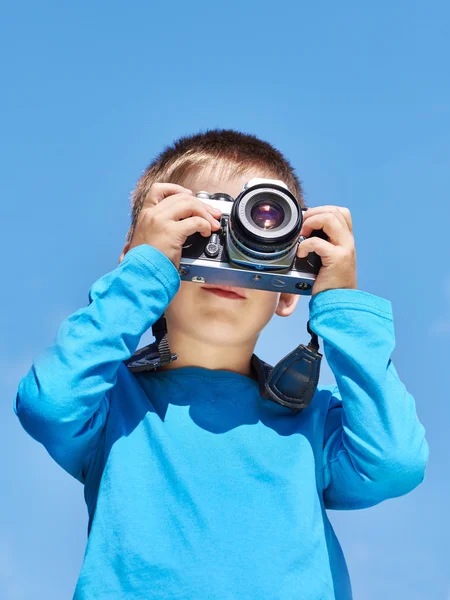 Liten pojke med retro Slr kamera på blå himmel — Stockfoto