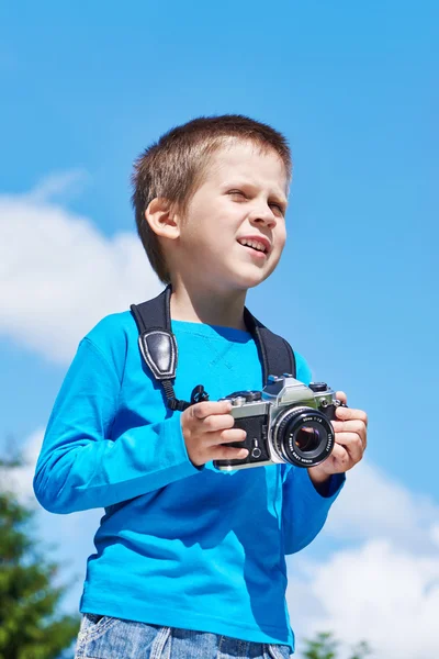 Malý chlapec s retro fotoaparát na obloze vypadá do vzdálenosti — Stock fotografie