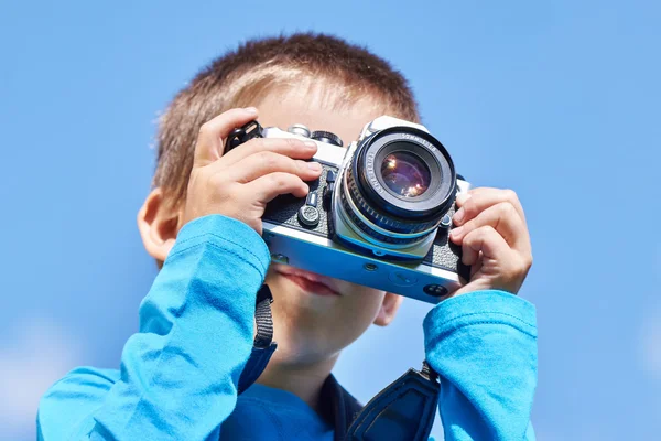 Little boy with retro SLR camera on blue sky — Stock Photo, Image