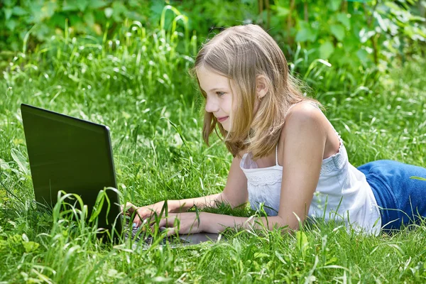 Girl using laptop on grass Stock Image