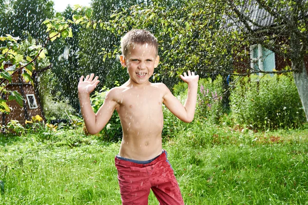 Happy little boy is jumping under rain — Stock Photo, Image