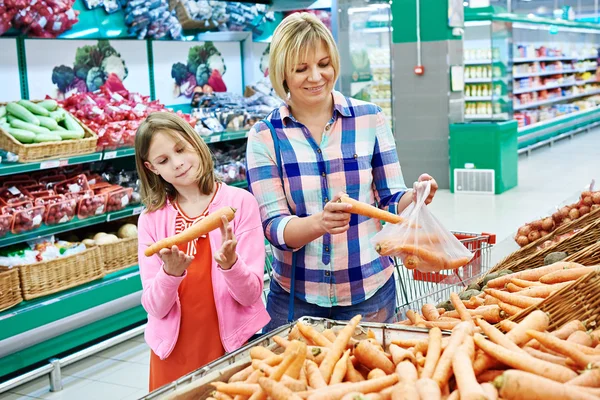 Мать и дочь выбирают морковь в супермаркете — стоковое фото