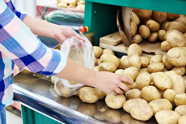 Woman puts potatoes in package — Stock Photo, Image