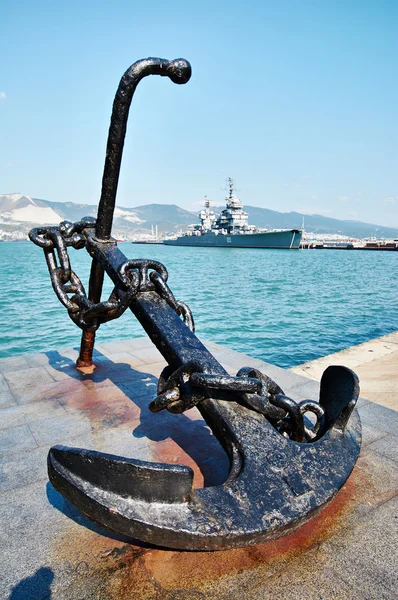 Anchor on embankment and cruiser in port — Stock Photo, Image