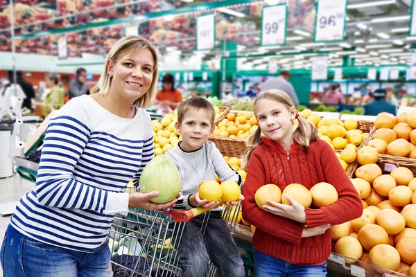 Mère et les enfants avec des ananas dans le département des fruits en super — Photo