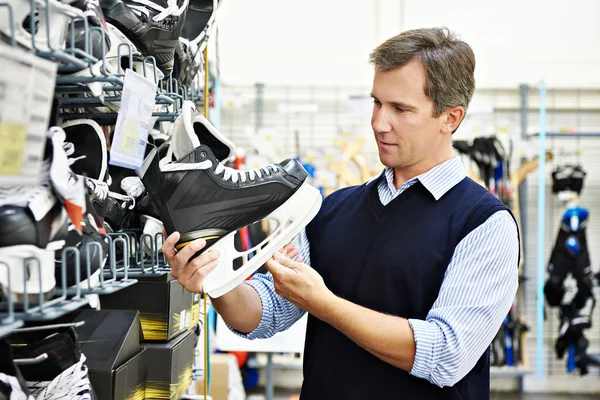 Hombre elige patines de hockey en tienda de deportes — Foto de Stock