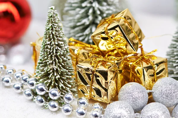 Подарки в золотой упаковке рядом с елками — стоковое фото
