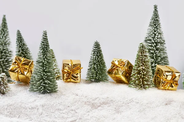 Christmas gifts in gold packaging near toys trees — Stock Photo, Image