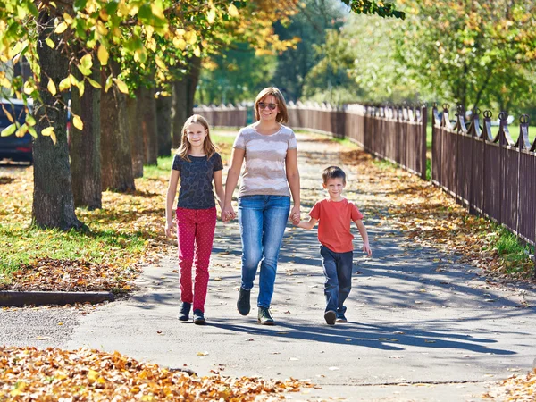 Mother with children walking in autumn park on sunny day — Stock Photo, Image