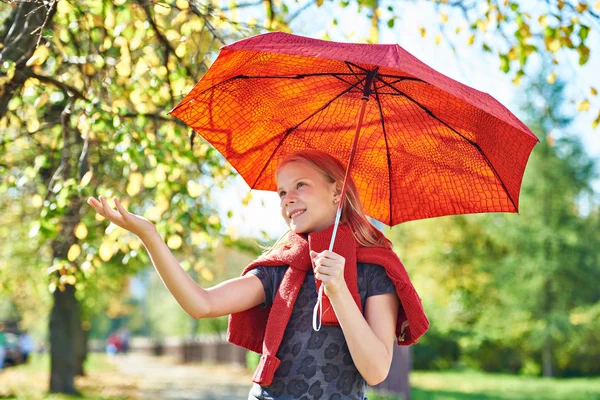 Joyeuse fille avec parapluie rouge dans le parc d'automne le jour ensoleillé — Photo