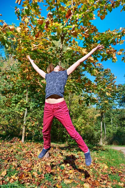 Девушка прыгает в красивом осеннем парке — стоковое фото