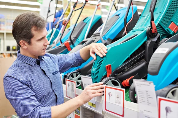 Man choosing lawnmowers in supermarket — Stock Photo, Image