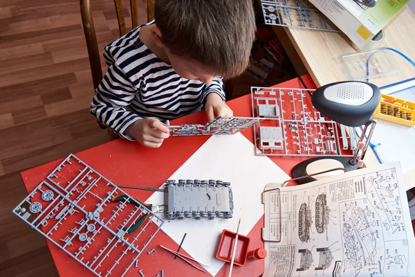 Маленький мальчик коллекционирует пластиковые модели танков — стоковое фото
