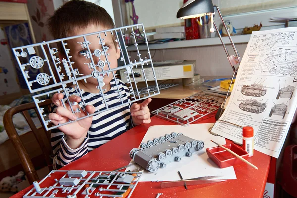 Kleine jongen verzamelt plastic model tank — Stockfoto