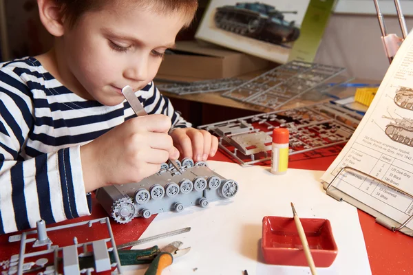 Kleiner Junge sammelt Plastikmodelltank — Stockfoto