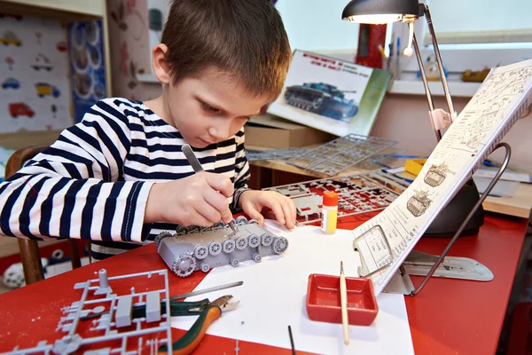 Маленький мальчик коллекционирует пластиковые модели танков — стоковое фото