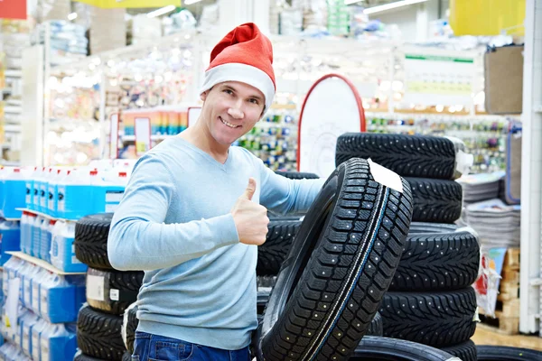 Felice uomo a Babbo Natale cappello con pneumatici invernali regalo in negozio — Foto Stock