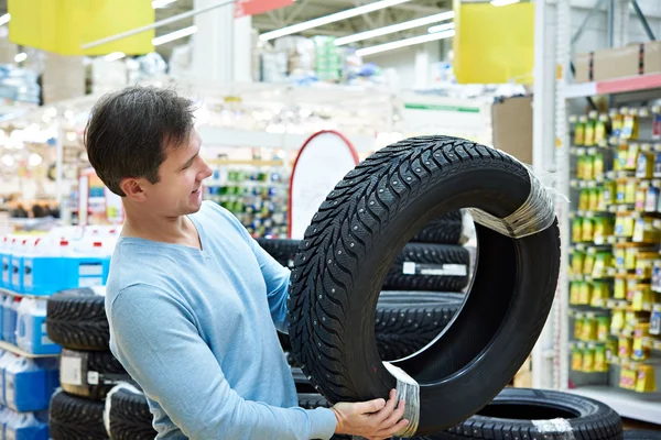 El hombre elige neumáticos con clavos de invierno para el coche en el supermercado —  Fotos de Stock