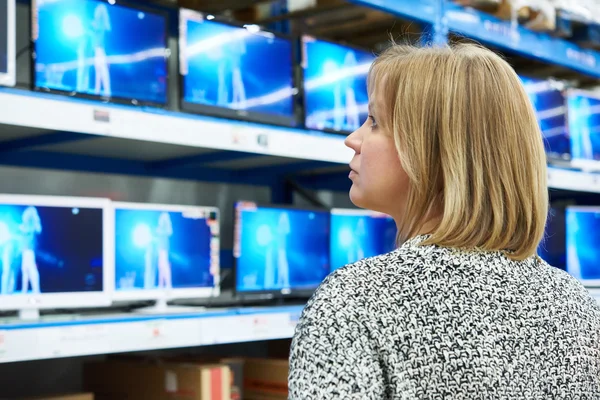 Mulher olha para TVs LCD na loja — Fotografia de Stock