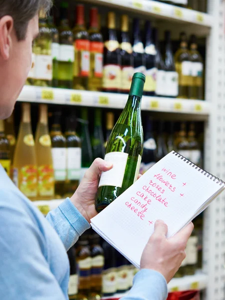 L'uomo sceglie bottiglia di vino bianco per data in negozio — Foto Stock