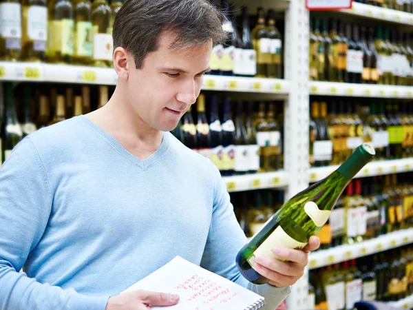 Mann wählt Flasche Weißwein für Date im Geschäft — Stockfoto