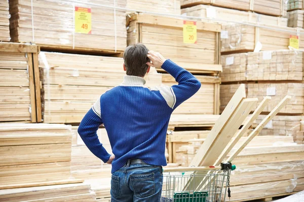 Man chooses boards for construction of store — Stock Photo, Image