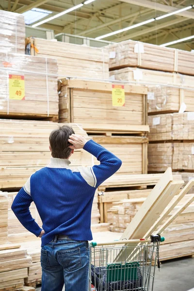 Man chooses boards for construction of store — Stock Photo, Image