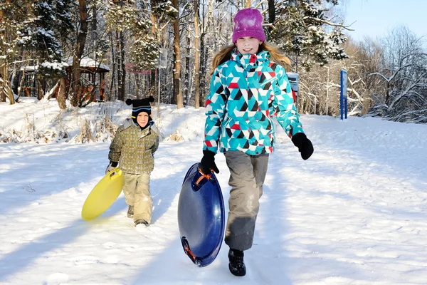 女孩和男孩与小山骑在雪橇上 — 图库照片