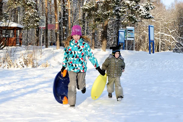 Girl and boy riding with hills on sleds — Stock Photo, Image