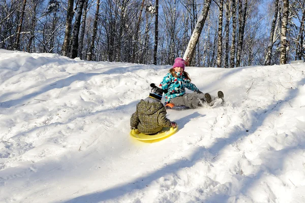 Girl and boy riding with hills on sleds — Stock Photo, Image