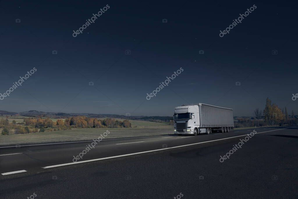 Truck driving through the night landscape at moonlight