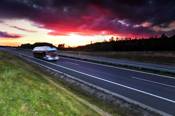 Vrachtwagen transport op de weg bij zonsondergang — Stockfoto
