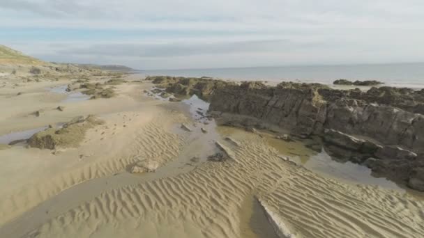 Vliegen over een zandige en rotsachtige strand. — Stockvideo