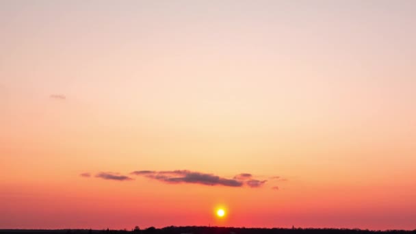 小さな雲とタイムラプス深紅の夕日 太陽は木の後ろに沈む — ストック動画