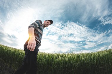 Young agronomist on a background of wheat. A man in a cap walks through an agricultural field