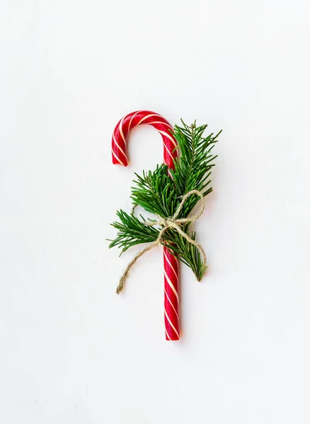 光の表面にモミの木の枝を持つロープで結ばれたキャンディーの杖を持つクリスマスの背景 あなたの挨拶のためのスペースを持つクリスマスの背景 — ストック写真