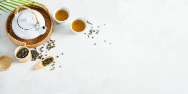 Asya çay konsepti, iki beyaz fincan çay ve çaydanlık yeşil kuru çaydanlıkla çevrili hafif arkaplan üzerine bir metin için. Geniş pankart.