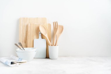 Mutfak arka planında yemek tabakları, fırında pişirme aletleri yuvarlanan raptiyeler, kesme tahtası, beyaz arka plandaki masada kaseler. Metin için boş alan, ev mutfağı dekor kavramı. 