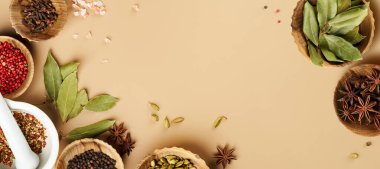 Çeşitli baharat koya yaprakları, kırmızı biber biberleri, ahşap kaseler içinde anason rengi fotokopi alanı olan bej renkli arka plan. Kopya alanı olan uzun yiyecek afişi.                              