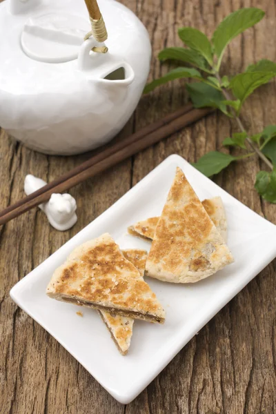 Chinesische Sesampfannkuchen mit orientalischer Teekanne im Hintergrund; nicht geschärfte Datei — Stockfoto