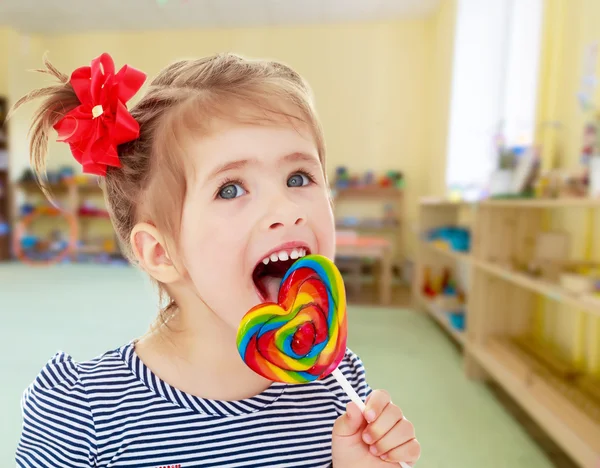 Girl licks candy on a stick — Stock Photo, Image