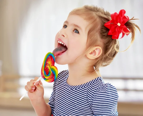 Mädchen leckt Bonbons auf einem Stock — Stockfoto