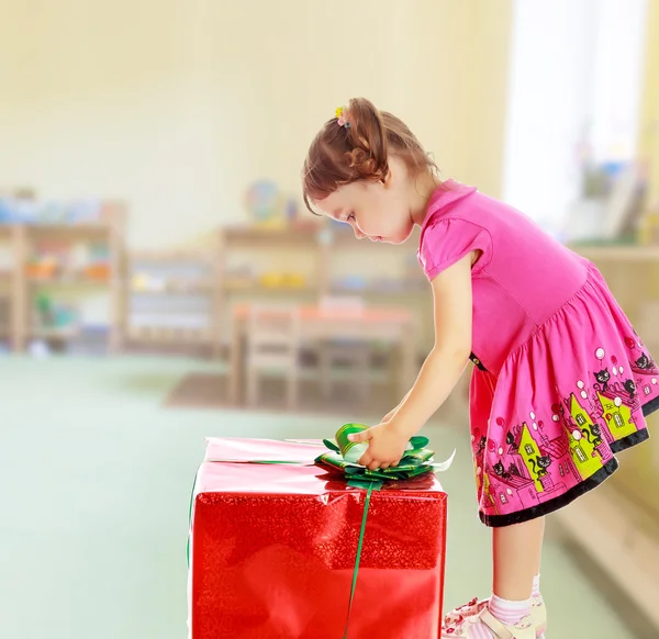 Kleines Mädchen schaut sich ein Geschenk an — Stockfoto