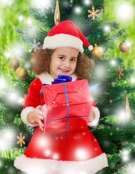 Niña cerca del árbol de Navidad con un regalo en sus manos — Foto de Stock